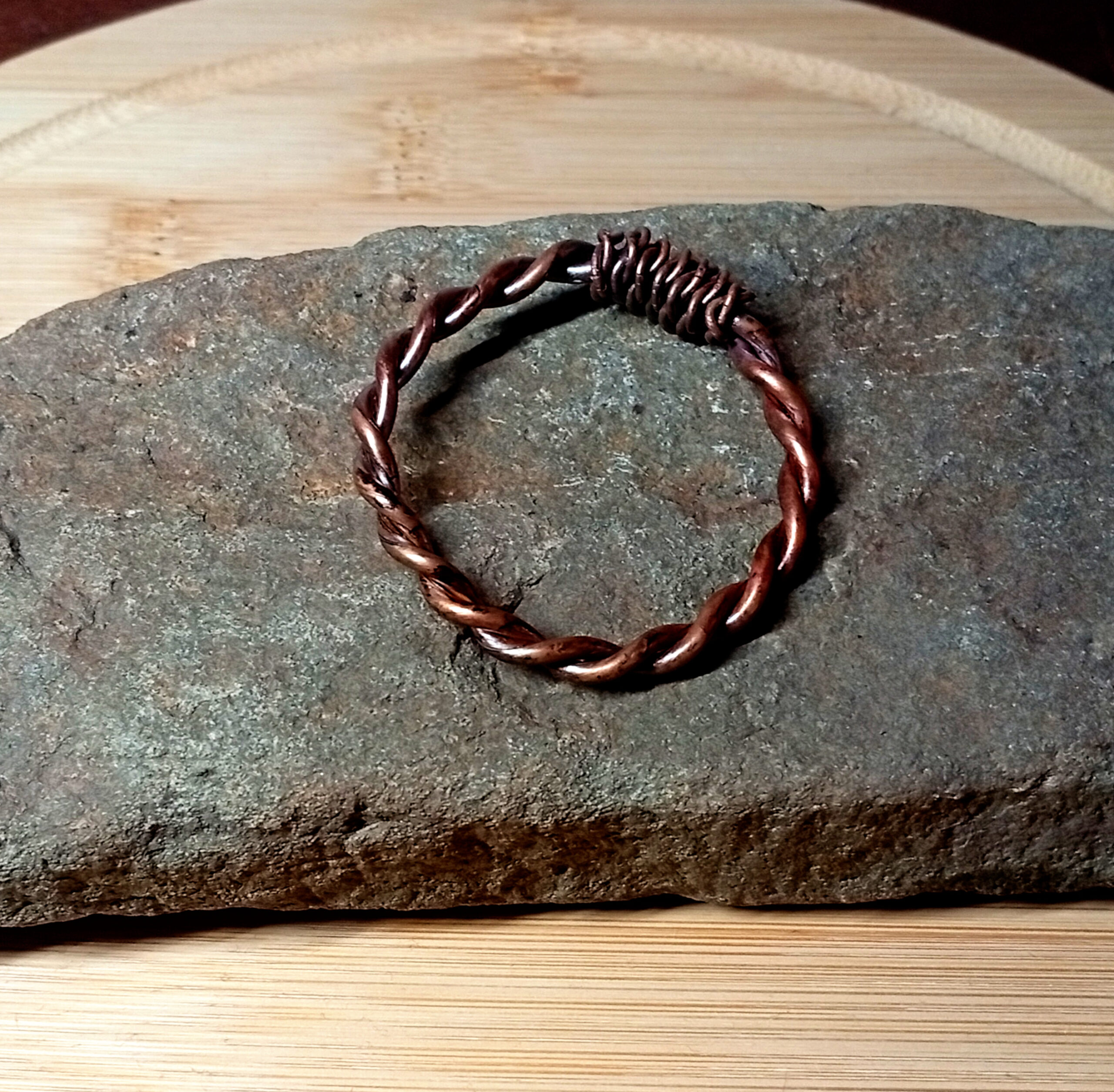 Handmade Bronze-Oil copper tensor ring placed on a grey stone slab