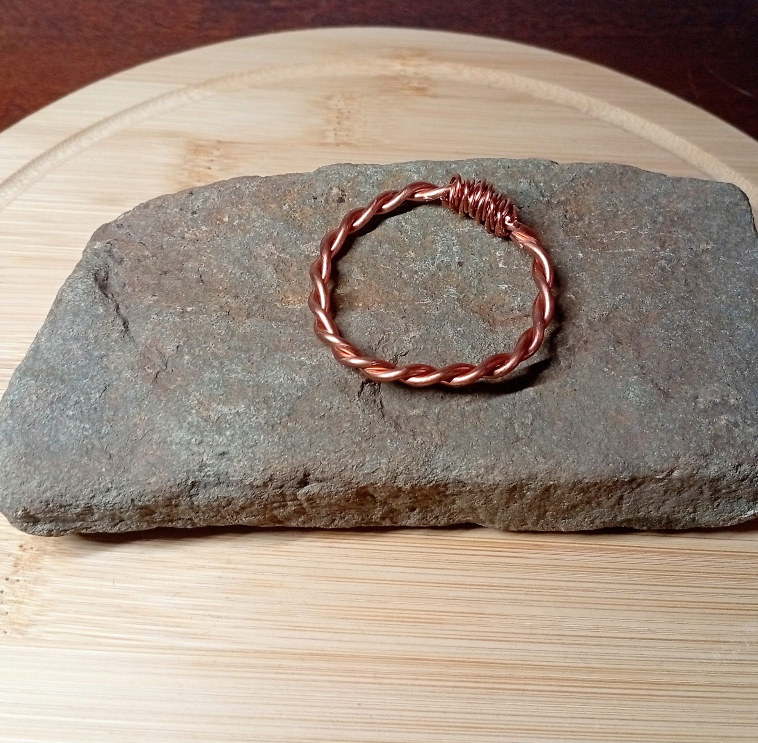 Close-up of RAW Copper tensor ring on bamboo board