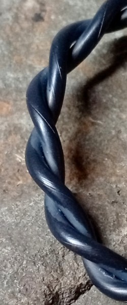 Close-up macro photograph of a twisted raw copper tensor ring.